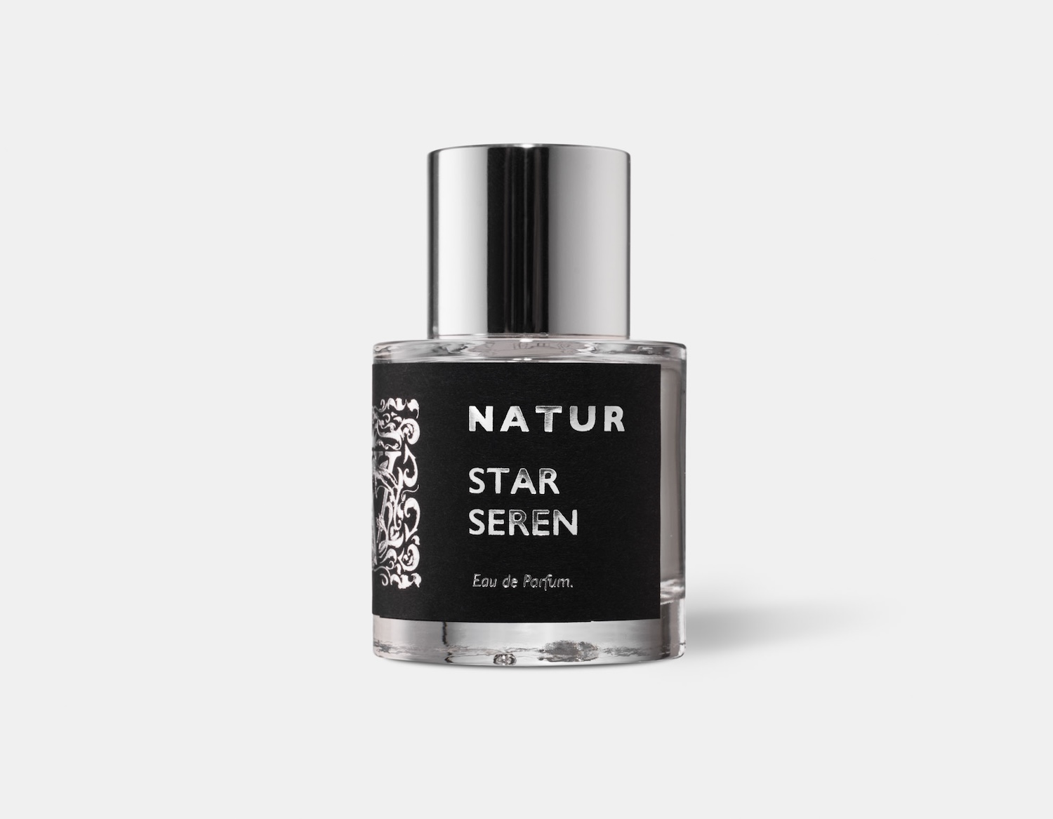 a cylindrical perfume bottle with a shiny silver cap, the bottle has a black label with silver foiled print saying Natur Star Seren, the collection and name of the perfume by Wales Perfumery