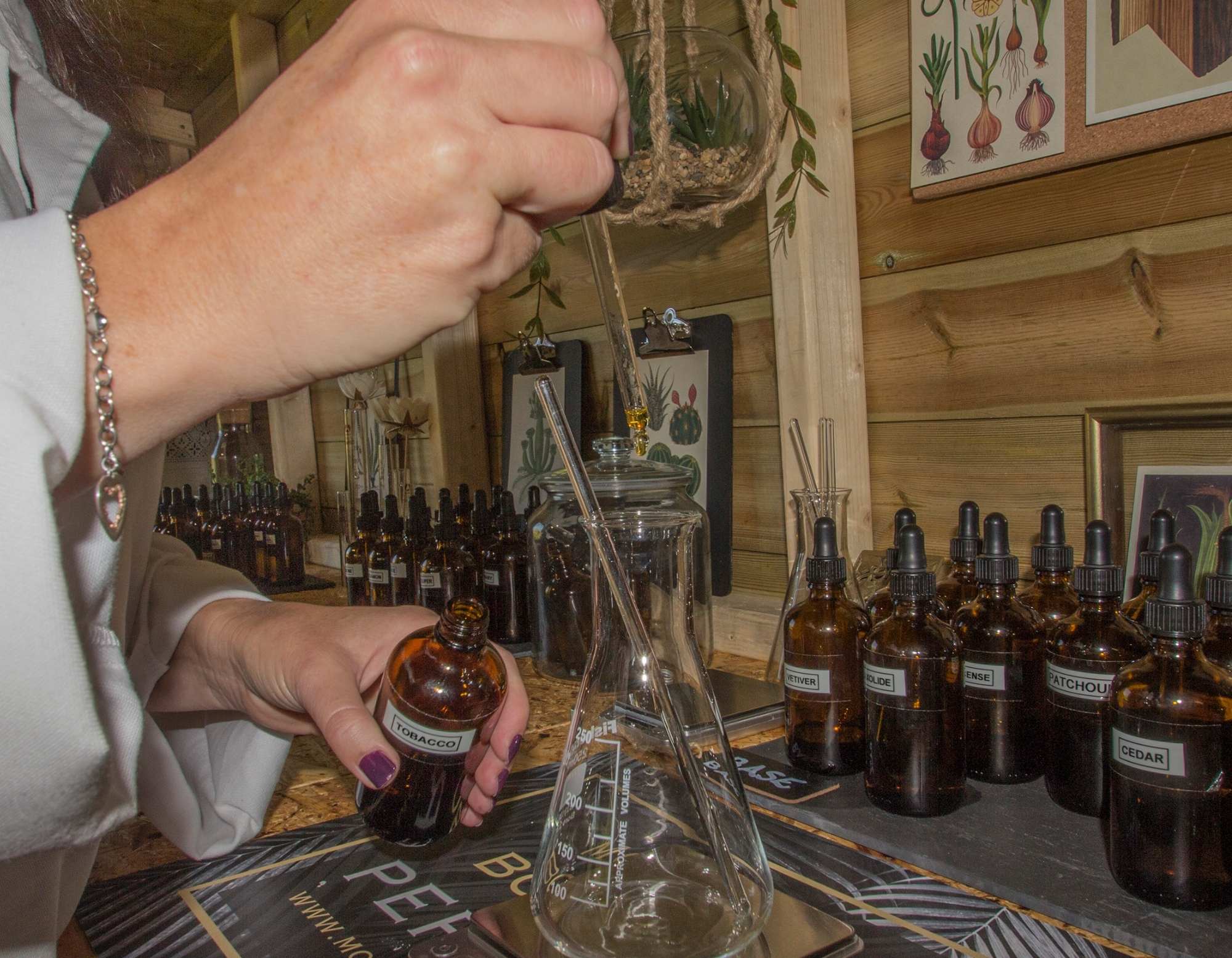 a perfumer's hands at work in the lab using a pipette