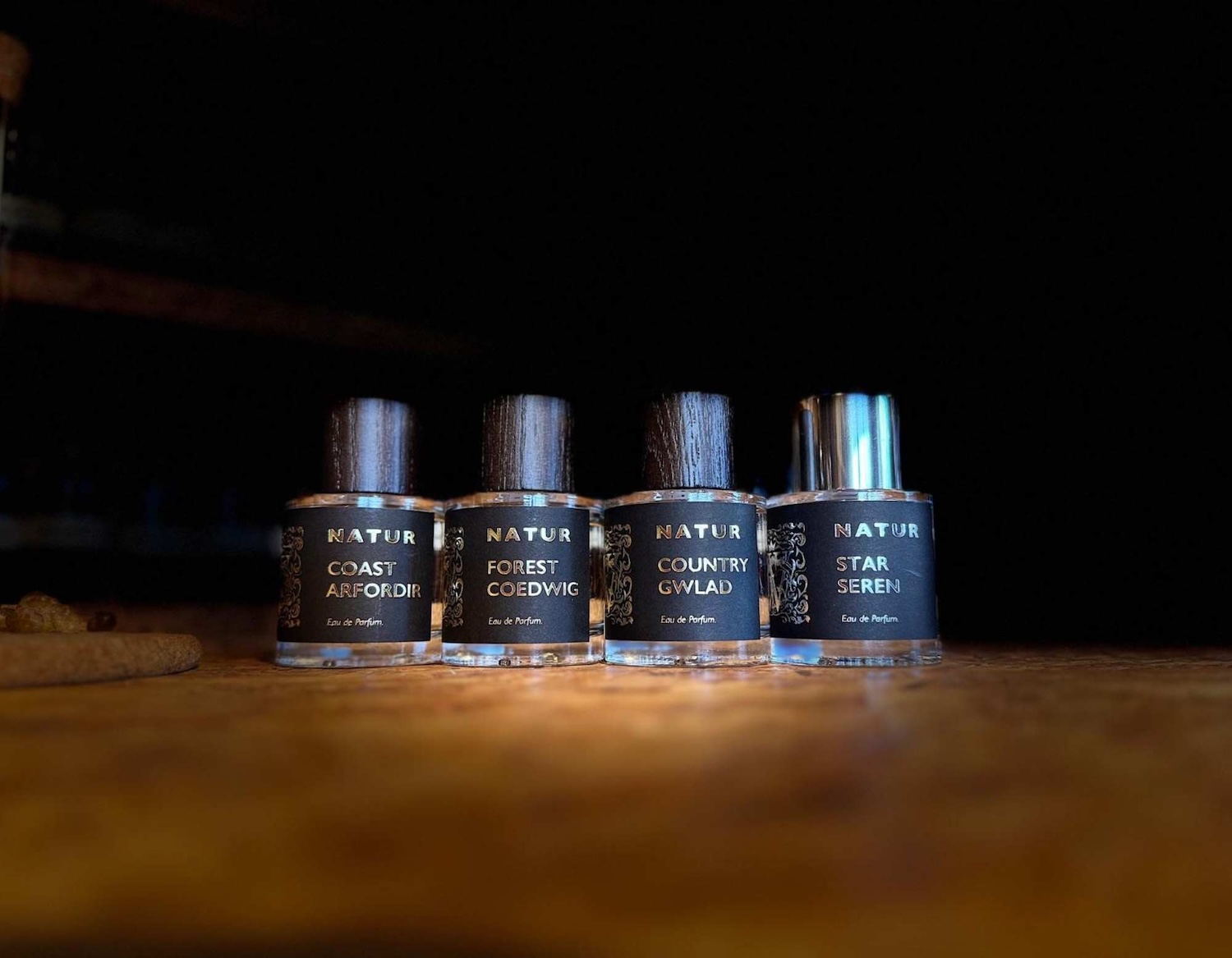 four bottles of eau de parfum, the bottles had black caps and labels and the lighting is dark and moody