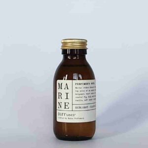 an amber glass bottle with a gold screw cap lid, and a cream paper label. the label says that this is a home fragrance diffuser in marine scent made by Wales Perfumery