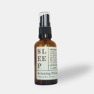 An amber glass spray bottle with a black pump lid and a cream paper label reading Sleep, Relaxing Pillow Spray, crafted by Wales Perfumery.