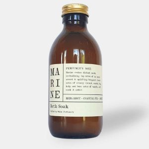 A 300ml amber glass bottle with a gold lid and a cream paper label reading Marine Môr Scented Bath Soak by Wales Perfumery.