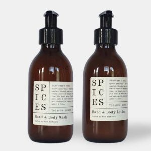two amber glass bottle with a black pump lids, and a cream paper labels. the label say that this is scented hand wash lotion set in spices scent made by Wales Perfumery