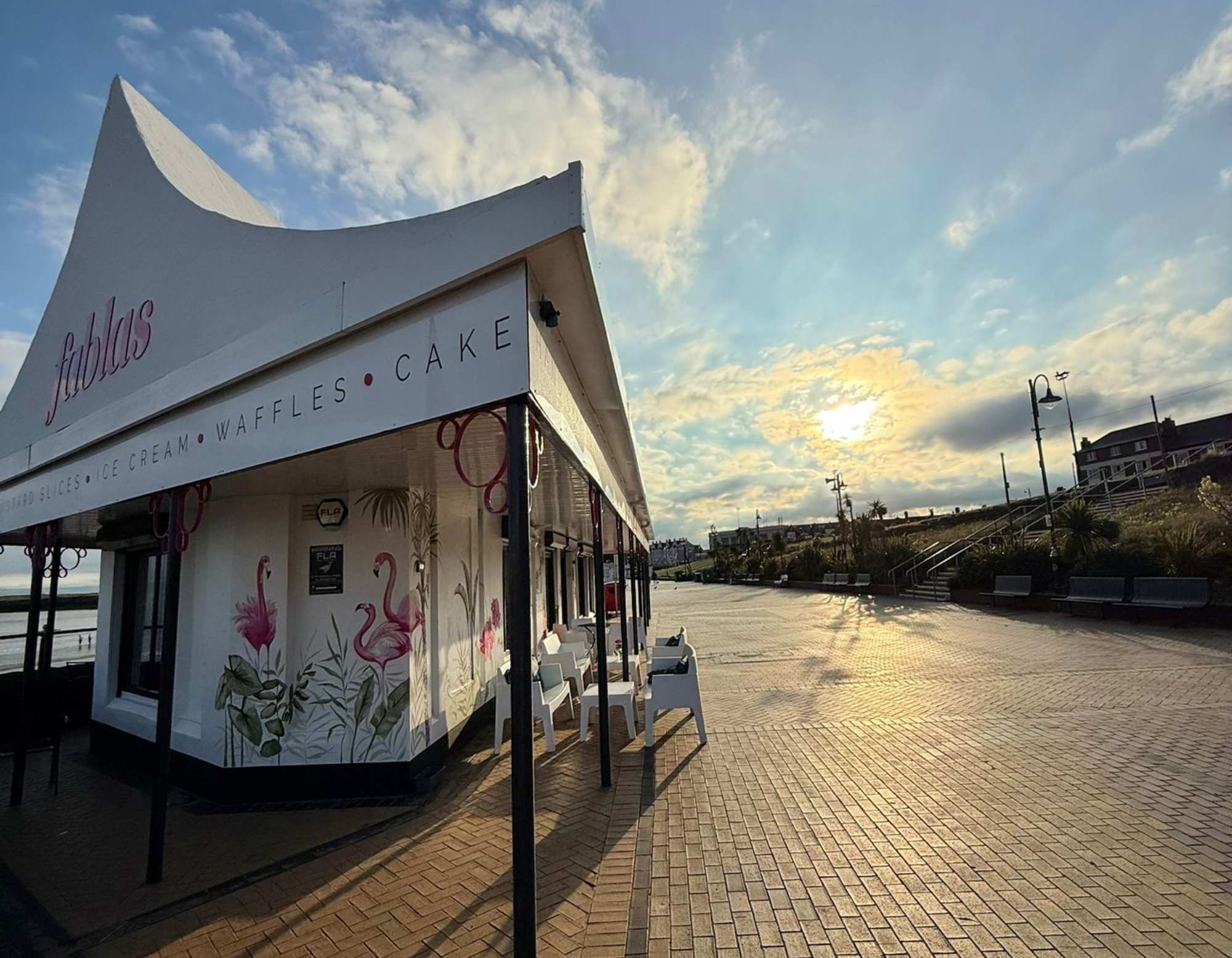 Fablas Ice Cream Parlour on Barry Island beach at sunset, with the seafront promenade in the foreground