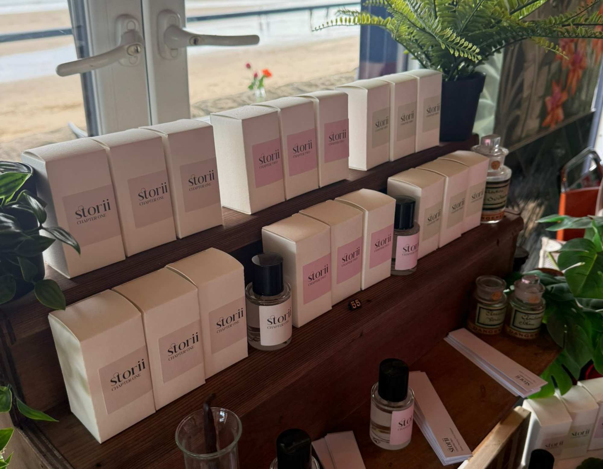 Storii by Wales Perfumery fragrance wardrobe on a tiered wooden display unit at Fablas Ice Cream Parlour, Barry Island, with the beach visible through the window behind