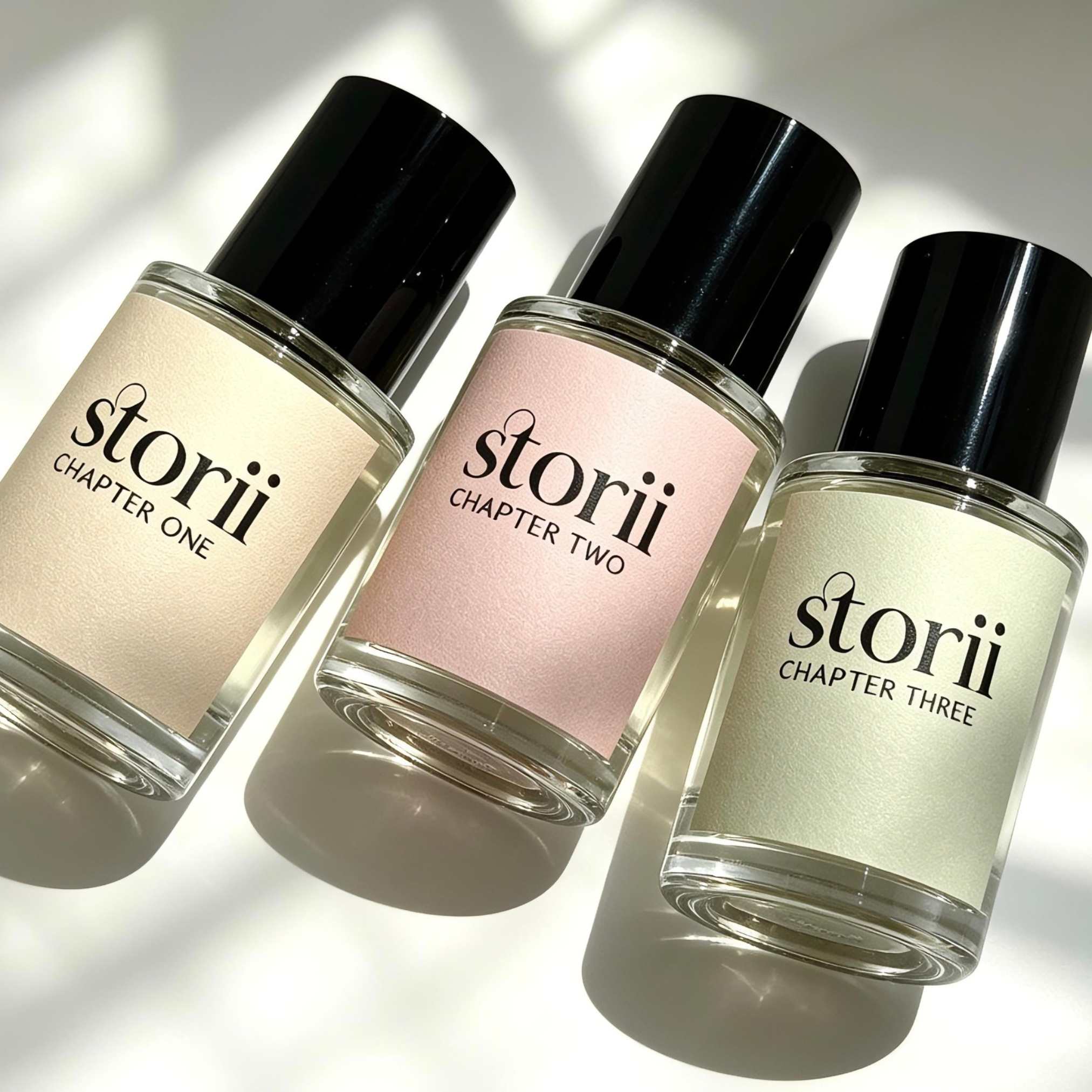 Three Storii 30ml perfume bottles, Chapter One, Chapter Two and Chapter Three, angled together in dappled natural light