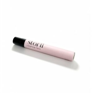 Storii Chapter Two 7ml perfume spray, pale pink label with black cap, lying diagonally on a white background