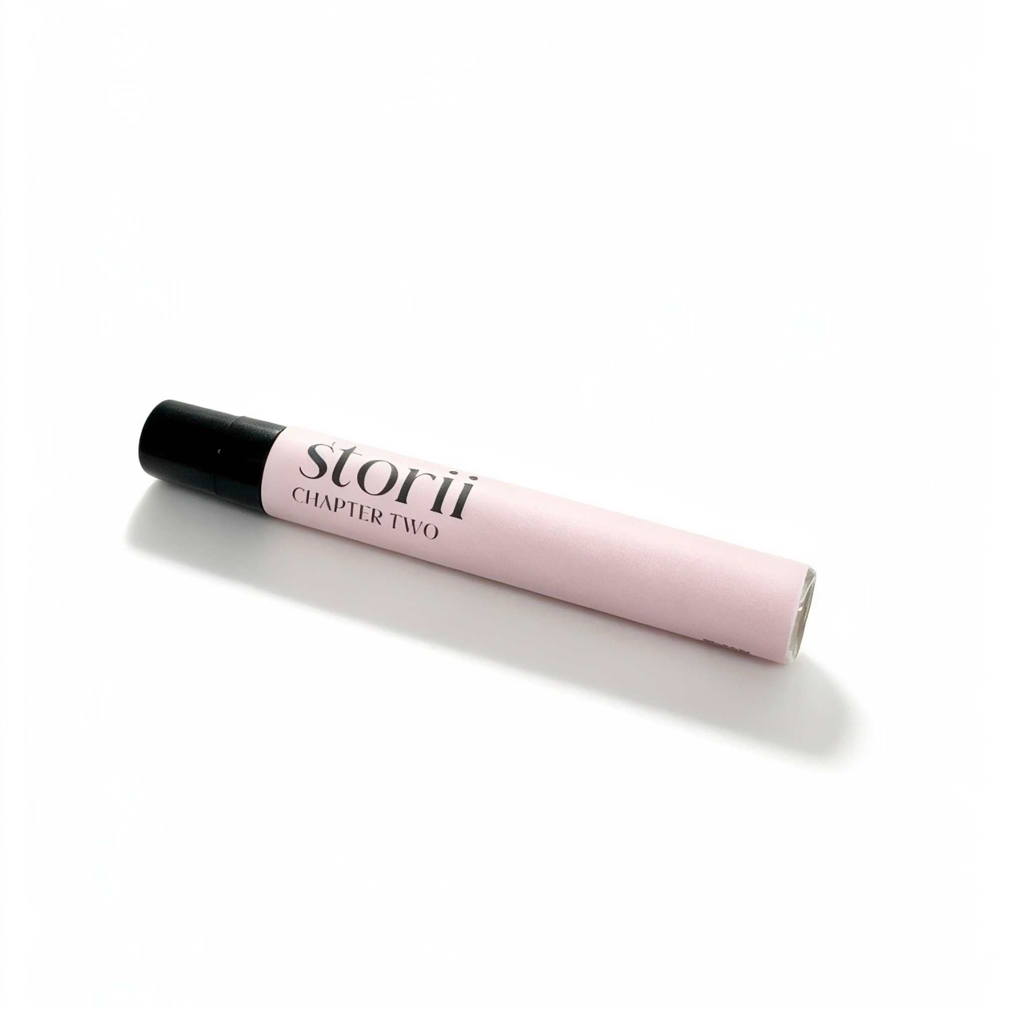 Storii Chapter Two 7ml perfume spray, pale pink label with black cap, lying diagonally on a white background