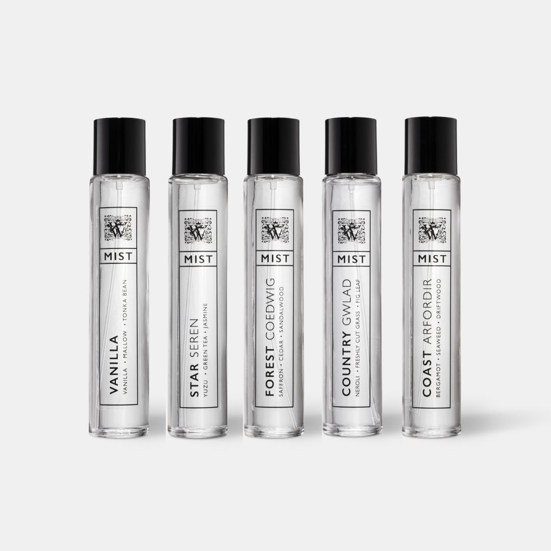 a collection of hair and body mists (eau de toilette) in clear bottles on an off white background
