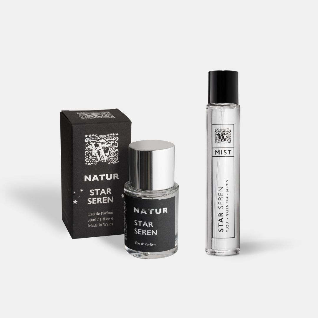 A Wales Perfumery Natur Star Seren 30ml Eau de Parfum in a clear glass bottle with a polished silver cap, alongside its black and silver gift box decorated with stars, and a slim Star Seren Mist featuring yuzu, green tea and jasmine, on a light grey background.